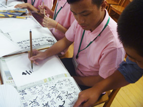 Image: Children learning Japanese calligraphy with Japanese middle school students